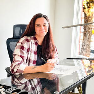 Artist Maria Vallverdu Sabia looking at the camera, drawing artpiece at her studio